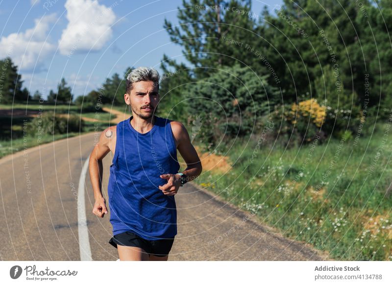 Determined man running on road during workout training fast exercise fitness young sport activity sportswear jog urban healthy body slim strong power