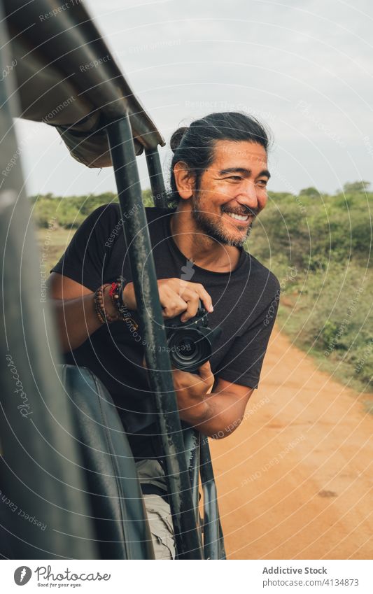 Ethnic male photographer taking picture on camera from car take photo safari man landscape travel wildlife nature photo camera memory ethnic traveler tourism