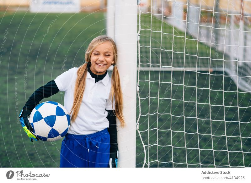 Happy young female player with ball in football arena at sports stadium girl soccer field uniform happy child kid club childhood athlete equipment smile preteen