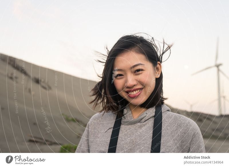 Young Asian woman standing on sea beach on windy weather skyline harmony sand touch hair coast thoughtful reflective calm coastline weekend recreation wistful