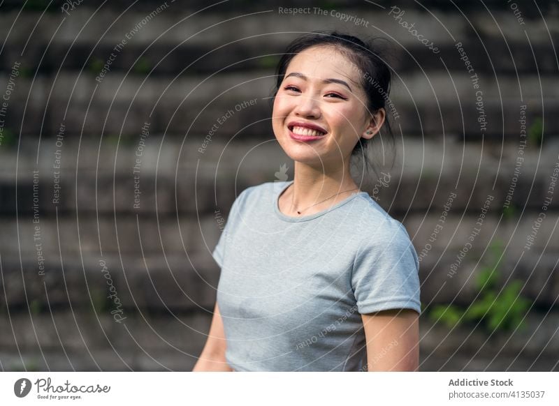 Positive ethnic woman sitting on shabby stairs in park staircase rest happy positive toothy smile casual sporty serene fit stone step style daytime confident