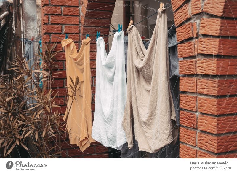 washed clothes man shirts hanging in front of house orange yellow pastel baby babyhood background blue childcare childhood clean clothespin clothing color