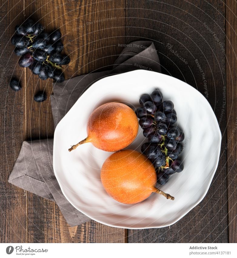 Fresh passion fruits and grapes in plate exotic fresh vitamin kitchen table natural raw bunch healthy food ingredient vegetarian tasty organic nutrition ripe