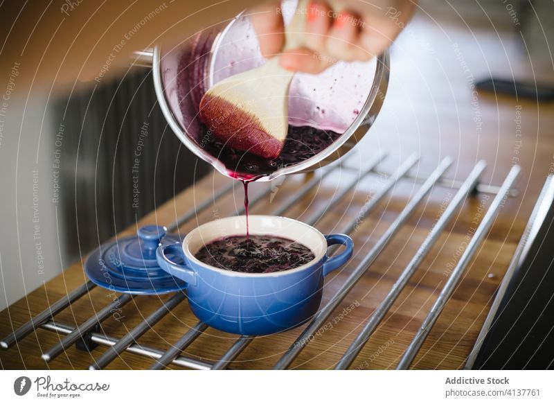 Woman preparing delicious berry jam blueberry prepare pour pot housewife homemade food sweet dessert breakfast ceramic crockery hand female fresh kitchen yummy