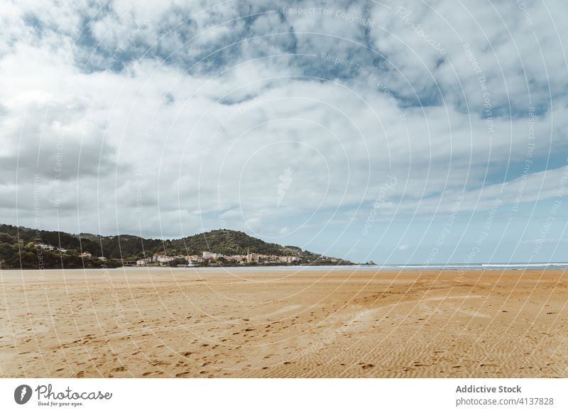 Sandy seashore near hill with houses under cloudy sky sand forest nature harmony picturesque idyllic hillside reserve beach serene horizon peace peaceful