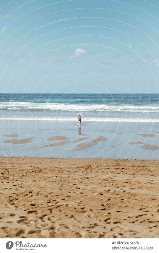 Unrecognizable tourist standing on sand sea beach under blue sky footprint shoreline spectacular harmony idyllic seascape horizon scenery nature wave