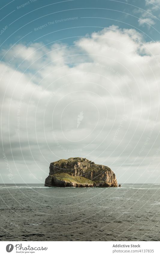 Rocky formation in center of sea under cloudy sky rock seascape breathtaking picturesque nature scenery magnificent beauty wave harmony rocky paradise skyline