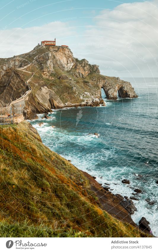 Rocky hillside near ocean under cloudy sky sea rock house wave picturesque seascape breathtaking nature idyllic harmony paradise skyline peaceful marine