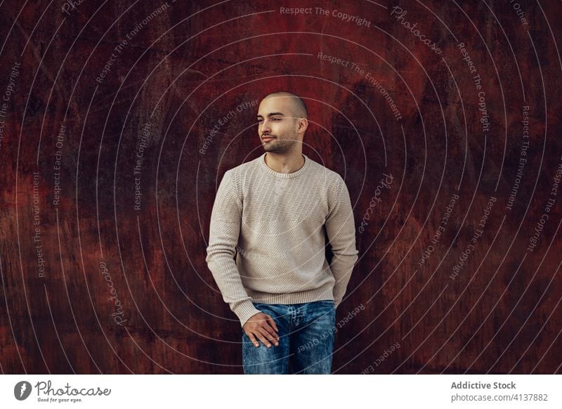 Hipster man standing while leaning on shabby fence pensive hipster style trendy modern street style thoughtful contemplate wall young unshaven guy jeans casual