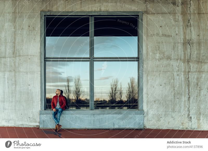 Young man in trendy outfit standing on street young modern confident jacket warm clothes pensive hipster unshaven autumn beard thoughtful think bald male