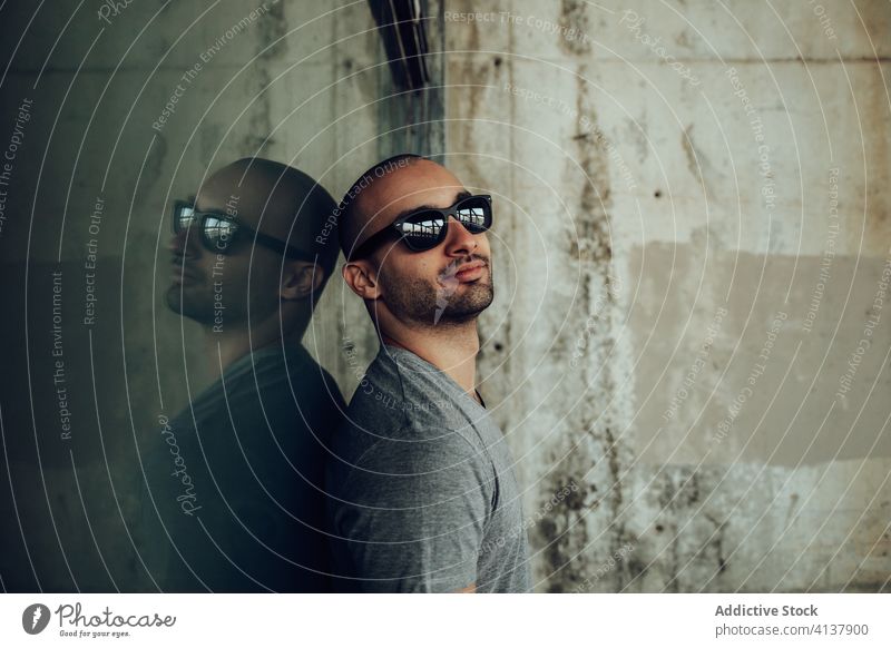 Young man in stylish clothes standing near weathered building young hipster style wall shabby pensive confident modern thoughtful male handsome guy casual alone