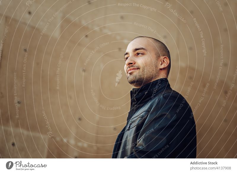 Stylish young man standing near building confident style casual modern bald wall urban street male black jacket trendy guy contemporary handsome happy fashion