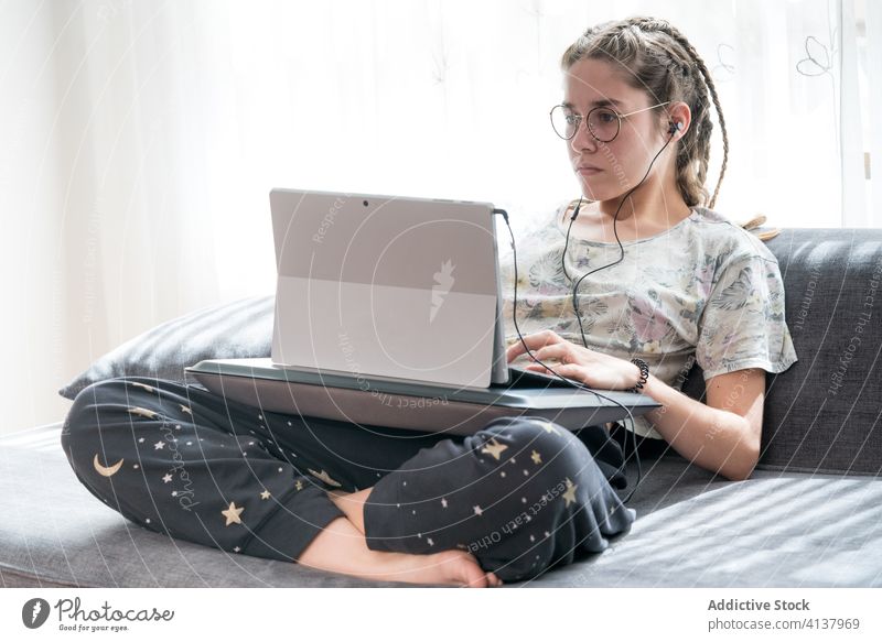 Young woman with headphones using laptop at home earphones young listen watch gadget online student casual video device internet browsing lifestyle connection