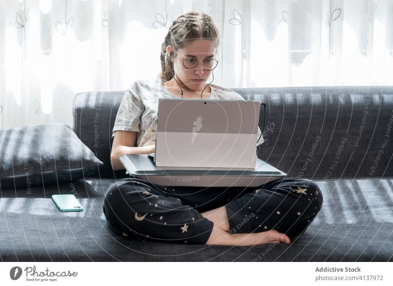 Young woman with headphones using laptop at home earphones young listen watch gadget online student casual video device internet browsing lifestyle connection