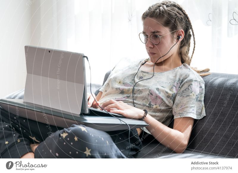 Young woman with headphones using laptop at home earphones young listen watch gadget online student casual video device internet browsing lifestyle connection