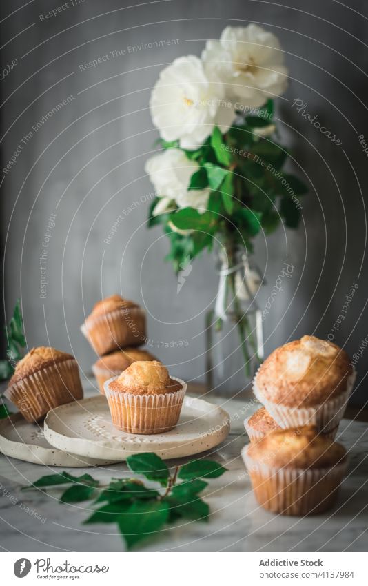 Delicious cupcakes in composition with bouquet of fragrant white flowers in vase on table food treat rose meal dessert pastry leaf fresh nutrition bloom