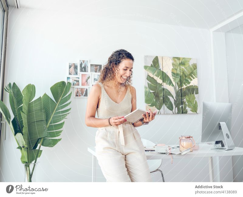 Cheerful woman reading notebook in office notes business smiling work table leaning female palma de mallorca spain style elegant trendy cheerful happy job