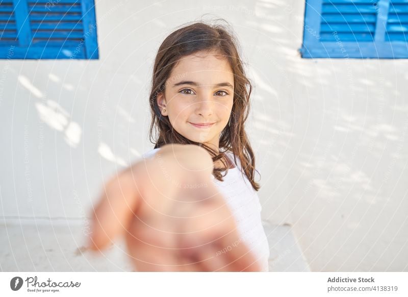 Positive girl with outstretched hand looking at camera invite smile positive kid follow me happy child portrait adorable preteen cheerful childhood charming