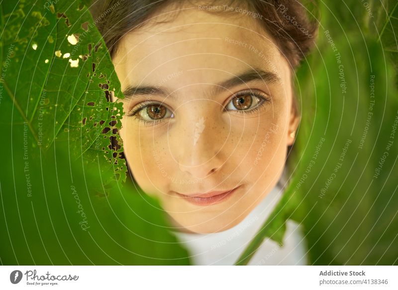 Smiling girl in green garden tree summer smile positive foliage kid portrait happy charming preteen brunette park nature fresh content child enjoy adorable