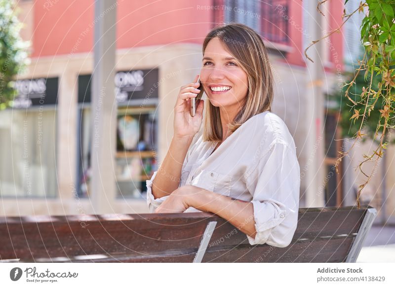 Stylish woman with mobile phone chilling on bench in summer day smartphone lifestyle using texting modern rest device gadget connection communicate online