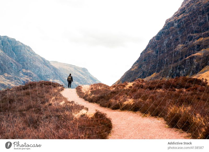 Traveler walking on pathway in mountainous terrain traveler highland hill trail sky activity landscape nature hiker glen coe scotland adventure journey trekking