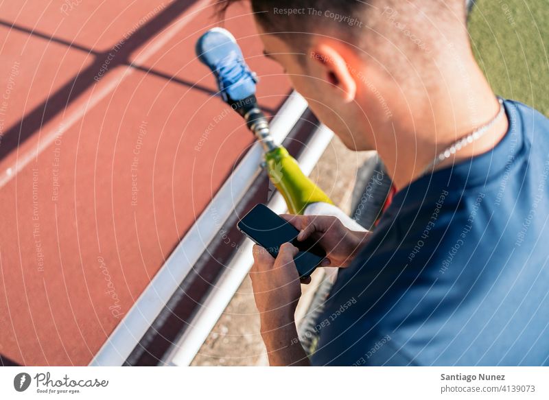 Disabled athlete using phone man runner unrecognized faceless sport prosthesis prosthetic disability disabled amputation amputee anonymous type typing