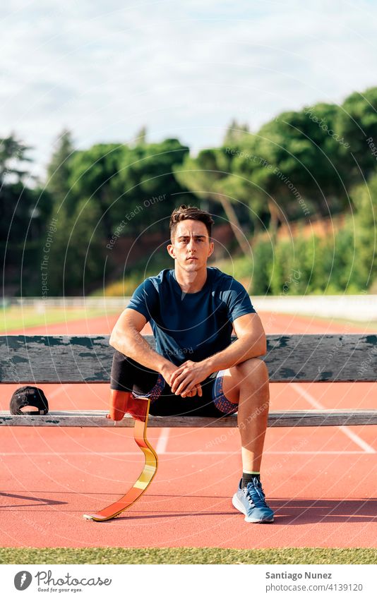 Disabled Man Athlete Resting bench sitting portrait boy looking at camera running track stadium athlete young man runner sport prosthesis prosthetic disability