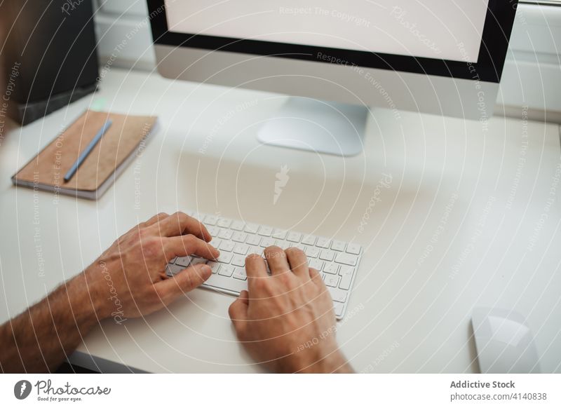 Anonymous male typing on keyboard on desktop computer project online man entrepreneur hands using freelance work home creative table workspace sit busy focus