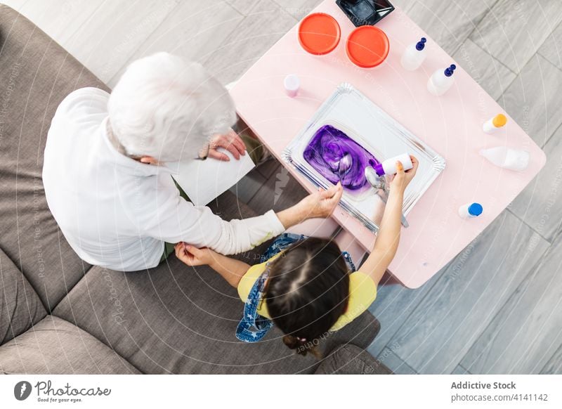 Grandfather and grandmother preparing bright slime with inks at home granddaughter fun make diy art craft add dye activity generation childcare process together