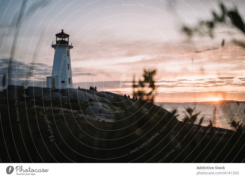 Unrecognizable people admiring sundown near lighthouse sea sunset sky cloudy admire silhouette peggys cove canada travel rest rock coast evening dusk twilight