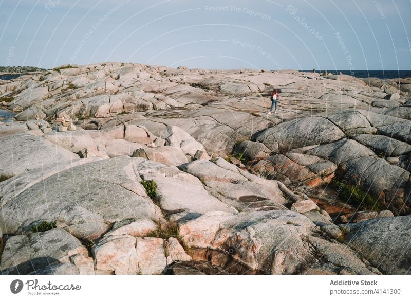 Unrecognizable woman standing on rocky seashore stone tourist sky cloudy peggys cove canada female explore rough coast overcast ocean weather trip nature