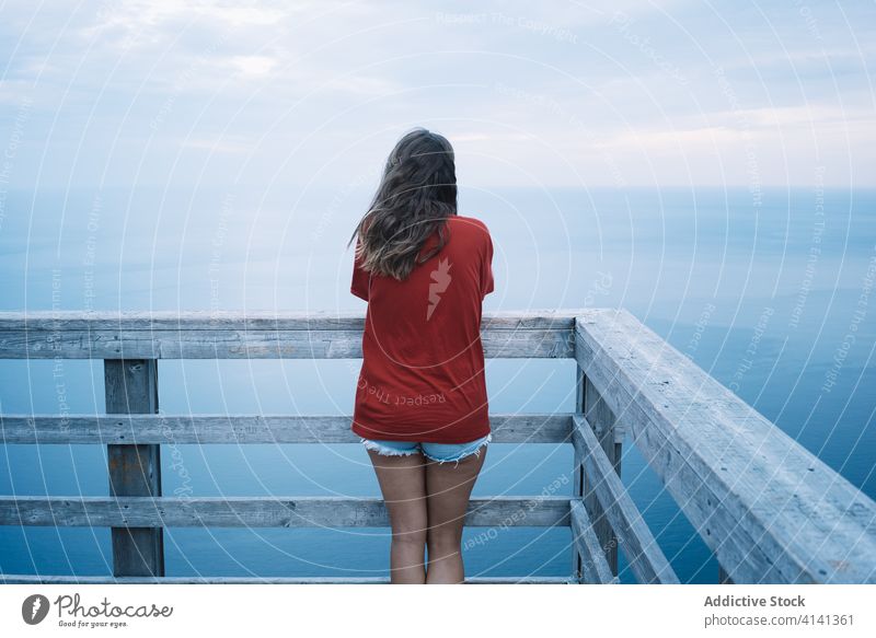 Woman on high terrace against seashore in sunset light woman lookout railing twilight ocean deck alone harmony national park evening la mauricie quebec canada