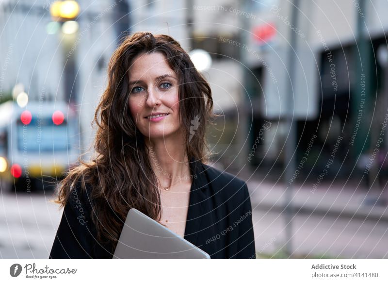 Businesswoman with laptop on city street entrepreneur businesswoman confident cityscape formal well dressed professional female cheerful content smile determine