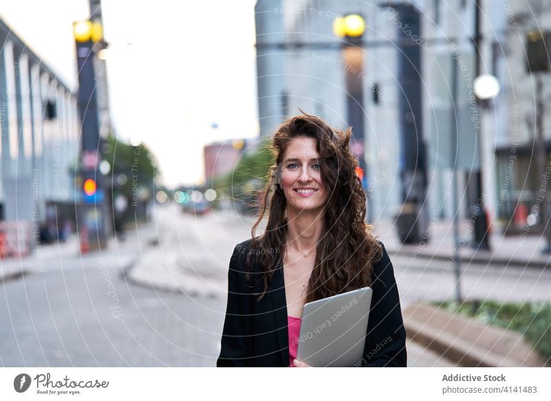 Businesswoman with laptop on city street entrepreneur businesswoman confident cityscape formal well dressed professional female cheerful content smile determine