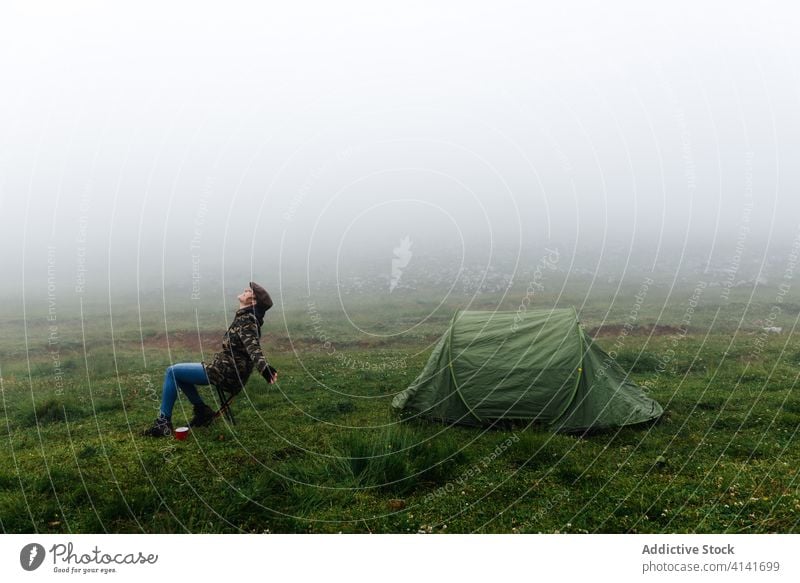 Woman in outerwear near camping tent in nature woman highland content relax traveler morning wanderlust freedom landscape harmony joy casual countryside cold