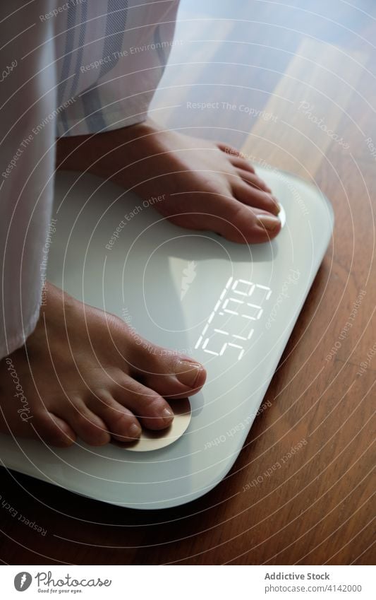 Crop woman standing on digital weight scales weight loss floor display bathroom smart healthy at home normal barefoot device wireless mobile pajama modern care