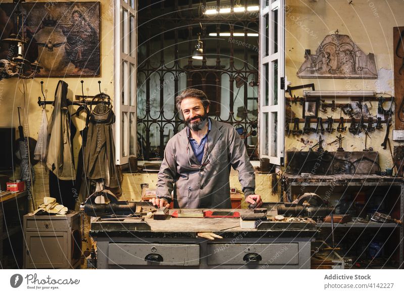 Front view of happy craftsman standing in studio clean engraving fabric golden frame artisan small business workshop process goldsmith ornament jeweler job