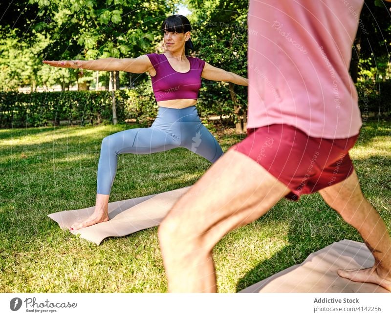 Calm couple practicing yoga in Warrior pose together warrior pose park barefoot sunny virabhadrasana training relationship tranquil healthy serene wellness