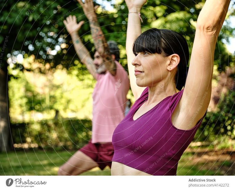 Calm couple practicing yoga in crescent pose together crescent variation lunge high lunge park barefoot sunny training relationship tranquil healthy serene