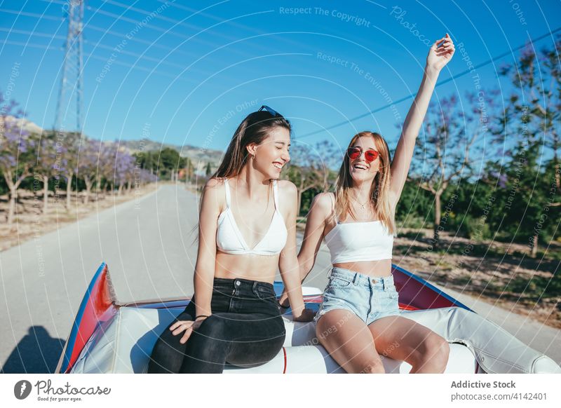 Delighted girlfriends having fun in summer on road vacation enjoy women cabriolet car carefree cheerful together holiday smile happy travel sit freedom nature