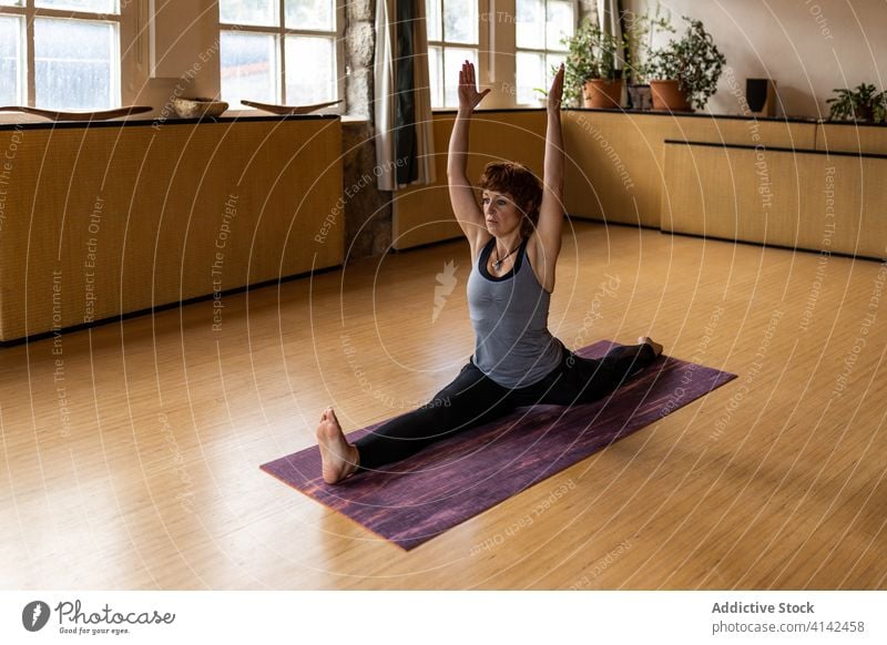 Flexible woman practicing yoga pose in studio practice monkey pose asana sit split flexible hanumanasana advanced position wellbeing female healthy concentrate