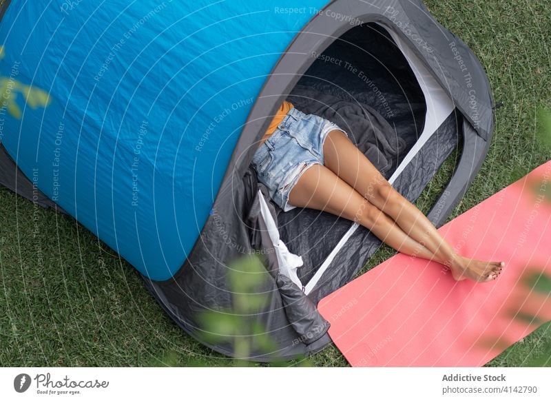 Young woman resting in camping tent relax summer enjoy nature meadow grass young leisure peaceful lawn season alone leg barefoot chill female casual vacation