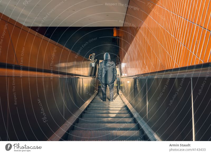 Berlin Underground, back view of a young man on an escalator berlin black clothing dark dirty downwards europe fear gangster germany grungy hands hoodie indoor