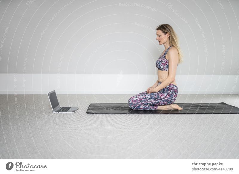 Woman doing yoga at home with laptop Yoga Online Notebook Digital Lifestyle Sports Athletic relaxation Mat Sit Blonde Computer Internet Leisure and hobbies