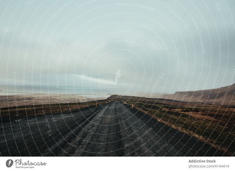 Breathtaking view of road near mountains under cloudy sky landscape empty highland straight idyllic scenery narrow abandoned natural tranquil silent ridge