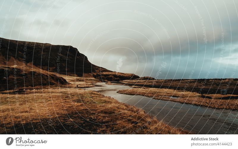 Rough grassy terrain with flowing river on overcast day landscape valley hill wild majestic nature mountain scenic calm iceland destination travel tourism