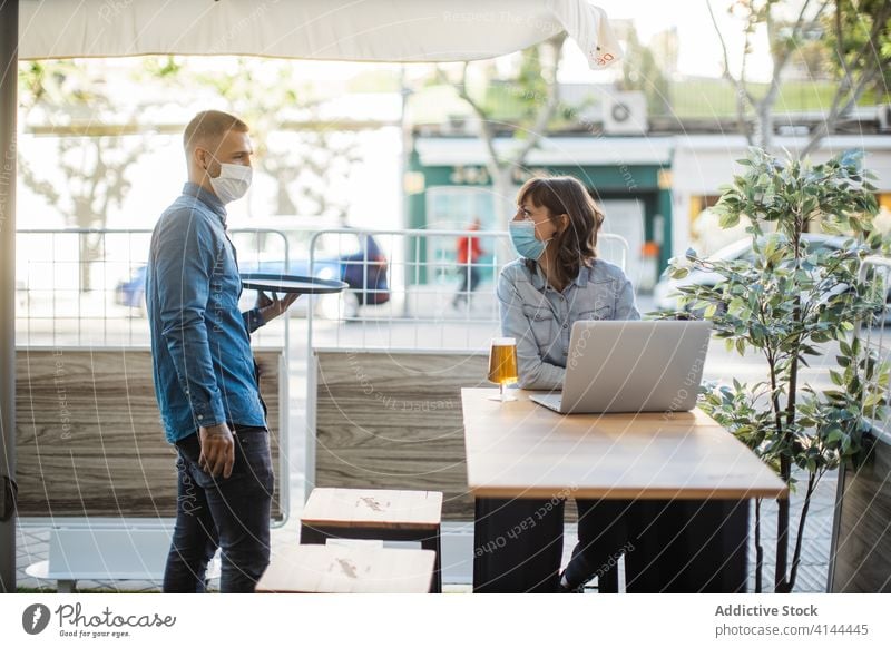 Female working on laptop in street cafe and waiting for order people serve beer fresh waiter client freelance coronavirus beverage device occupation job remote