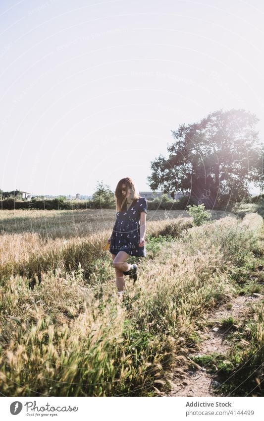 Cheerful woman walking along field run countryside carefree weekend summer sunny freedom cheerful female rubber boot dress joy meadow nature harmony idyllic