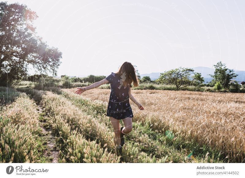 Cheerful woman running along field countryside carefree weekend summer sunny freedom cheerful female rubber boot dress joy meadow nature harmony idyllic grass