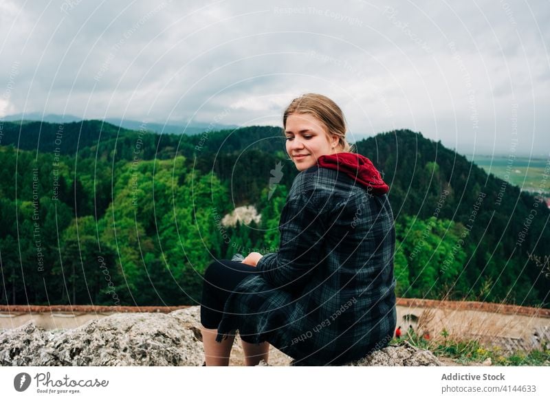 Carefree woman resting on high viewpoint against picturesque grassy hills traveler majestic highland scenery amazing smile carefree breathtaking admire